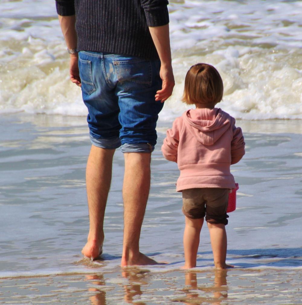  vader aan het strand met kind, genieten van de zee