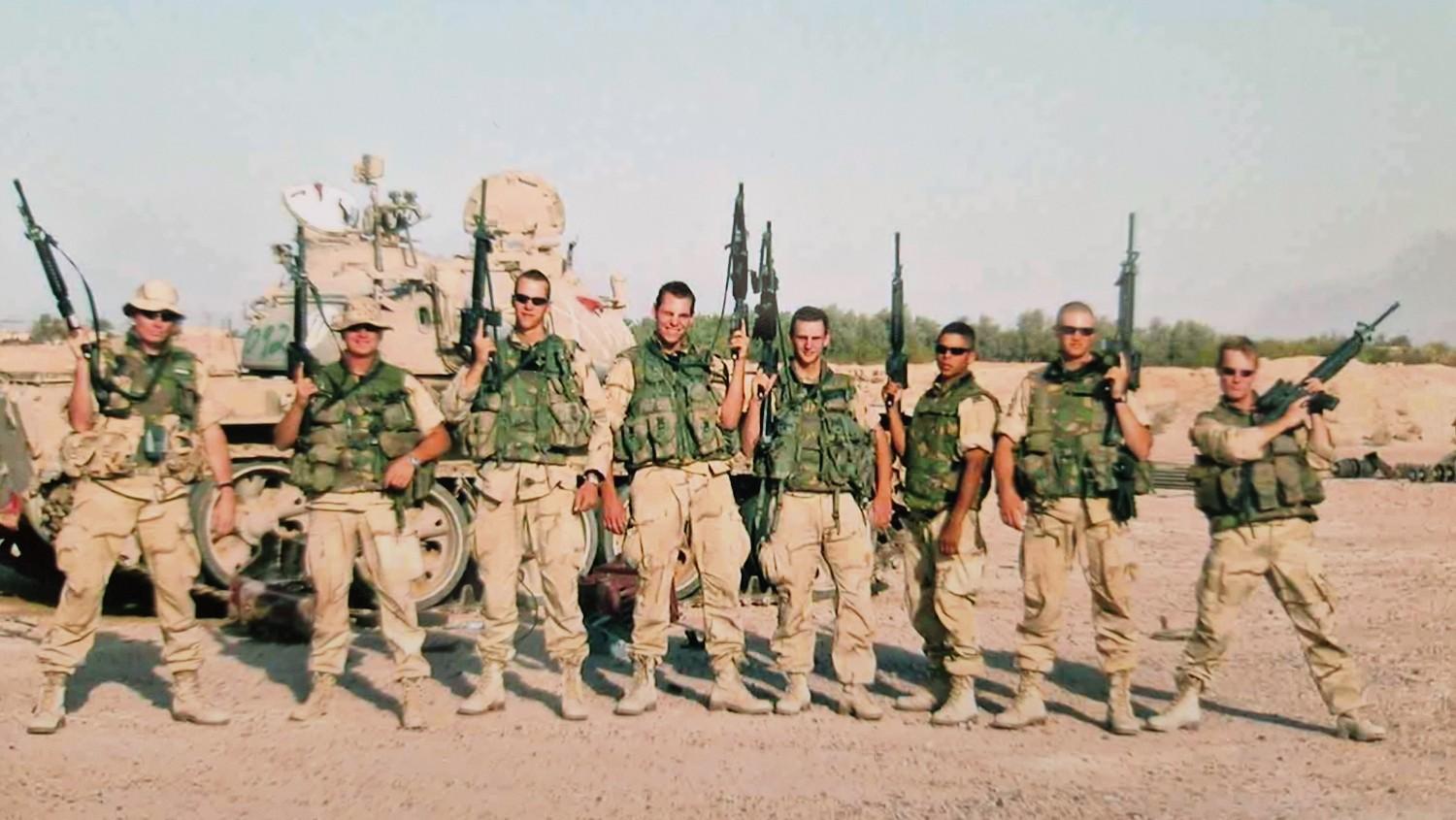 Oud-mariniers staan naast elkaar met geweren in de hand.
